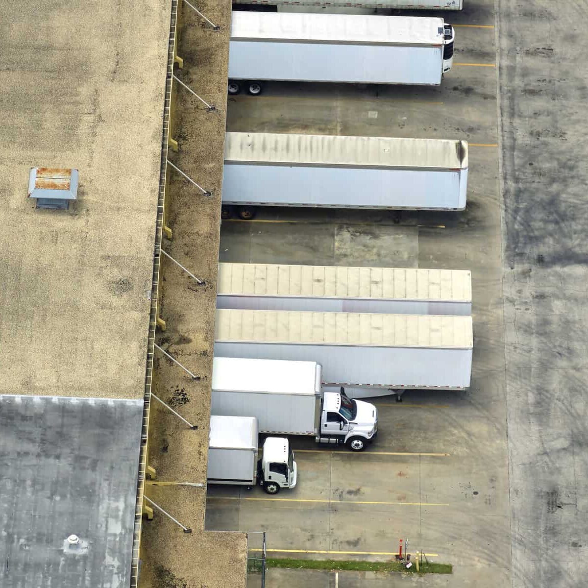 Aerial view of large commercial distribution center with many trucks unloading and uploading retail products for further shipment. Global economy concept.