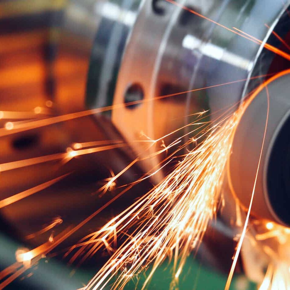 sparks flying while machine griding and finishing metal in factory